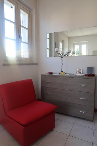 una sedia rossa in una stanza con cassettiera di La casa di Ale ad Arezzo