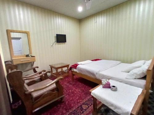 um quarto de hotel com duas camas e uma mesa e cadeiras em Madina Hotel 2 em Gilgit