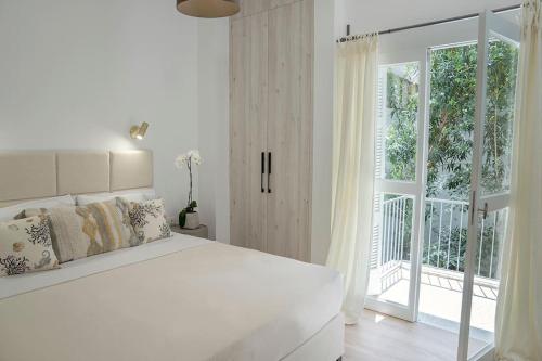 um quarto branco com uma cama e uma grande janela em Romantic apartment with hot tub next to Acropolis em Atenas