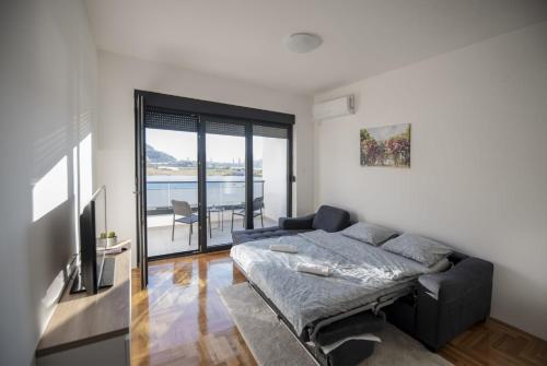 a bedroom with a bed and a couch and a balcony at APARTMAN DERETIC in Trebinje