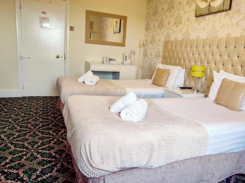 two beds in a hotel room with towels on them at Wentworth House - Free Parking in Bath