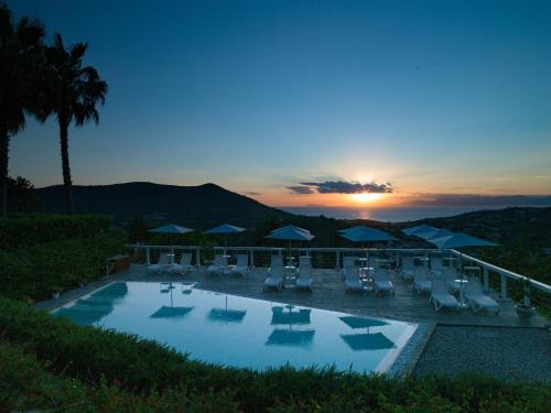 ein Pool mit Stühlen und Sonnenschirmen bei Sonnenuntergang in der Unterkunft La Frescura del Principe Dimora di Charme in Agropoli