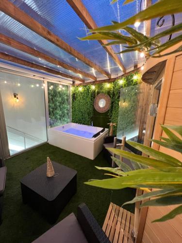 een kamer met een bad en een patio met een plant bij SPA de charme 6 pers avec Jacuzzi & Sauna privatifs au coeur de ville - Esprit Coco in Mulhouse