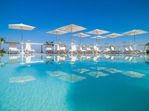 una piscina con sillas y sombrillas blancas en La Frescura del Principe Dimora di Charme, en Agropoli