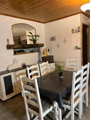 comedor con mesa negra y sillas blancas en Gîte des reculées, en Ladoye-sur-Seille