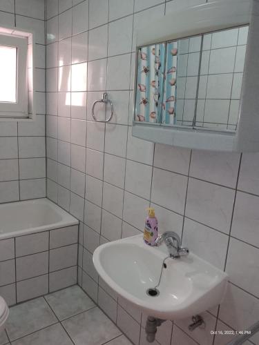 a white bathroom with a sink and a mirror at Apartman Tomić - Copacabana Beach Okrug Gornji in Okrug Gornji