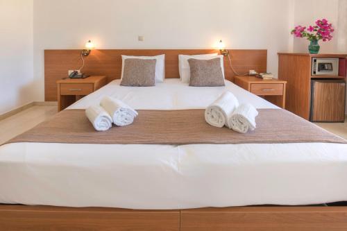 a bedroom with a large white bed with towels on it at Sami Beach Hotel in Sami
