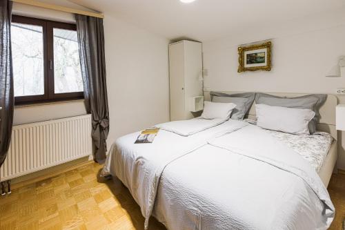 a bedroom with a white bed and a window at Quercus Apartments Bled in Bled