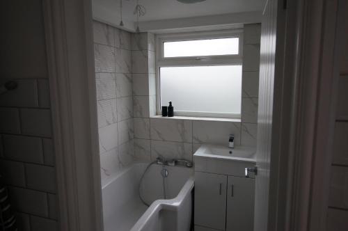 a bathroom with a tub and a sink and a window at 3 Bed 2 Lounge House up to 40pc off Monthly in Addlestone by Angel and Ken Serviced Accommodation Great Value for Long-term Stay in Addlestone