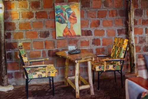 a table with two chairs and a painting on a brick wall at Kilimanjaro Scenic Homestay in Moshi