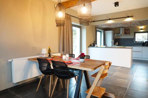 een keuken en eetkamer met een houten tafel en stoelen bij Gîte XXV House - 4 personnes in Héron