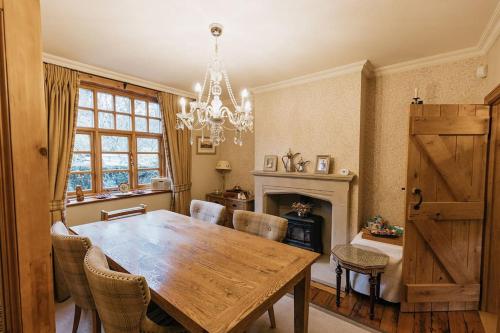 a dining room with a wooden table and a chandelier at STATION COTTAGE - Unique Accommodation with River Flowing through Garden in Bolton Abbey