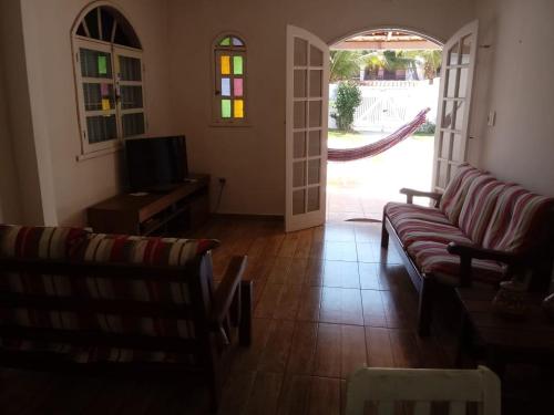 Sala de estar con 2 sofás y TV en Aluguel Temporada CABO FRIO, en Cabo Frío