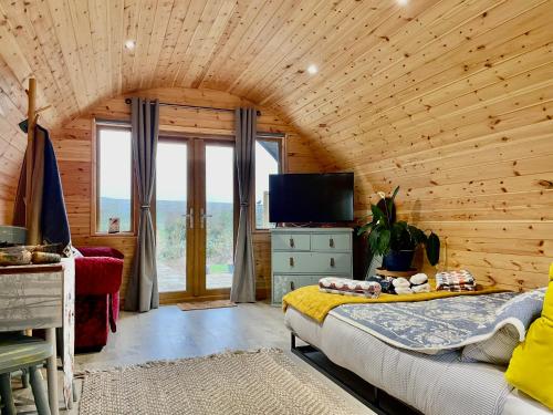 1 dormitorio con techo de madera, 1 cama y TV en Park Hill Pod, en Stratford-upon-Avon
