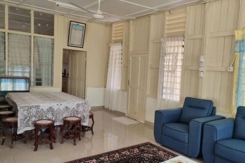 a living room with a table and blue chairs at Teratak An Nur: A village on top of the hill in Kuala Pilah