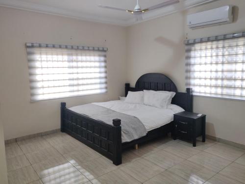 een slaapkamer met een bed en 2 ramen bij Lakeside Lodge in Apenkwa