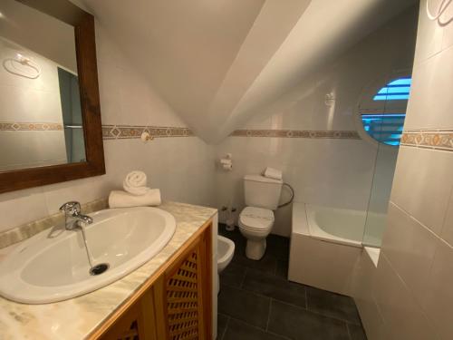 Un baño con lavabo, inodoro y espejo. en Duplex 3 dormitorios en plaza de Andalucía, en Sierra Nevada