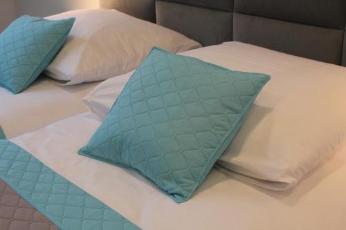 a bed with two blue pillows on it at Apartament AQUA MAZURY in Ełk