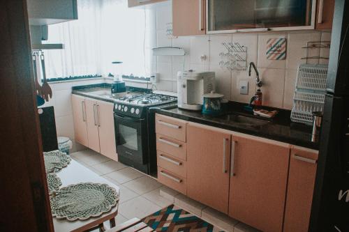 uma cozinha com um lavatório e um fogão forno superior em Apartamento Rio das Ostras, Extensão do Bosque em Rio das Ostras