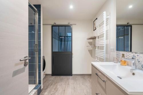 een badkamer met een wastafel en een glazen deur bij Superbe appartement avec parking gratuit in Lons-le-Saunier