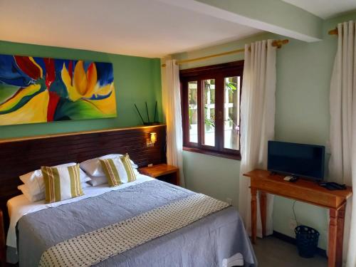 a bedroom with a bed and a tv and a window at Casa Verde Río in Rio de Janeiro