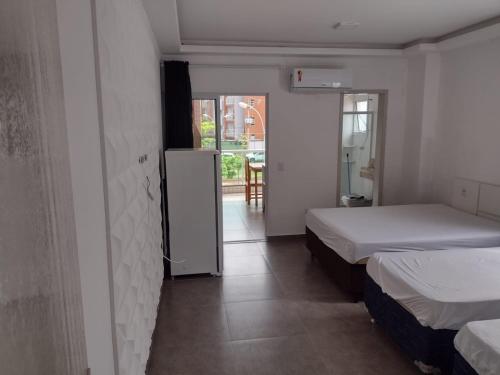 um quarto com 2 camas e uma porta para um pátio em Apartamento Cereja do Mar em Ubatuba