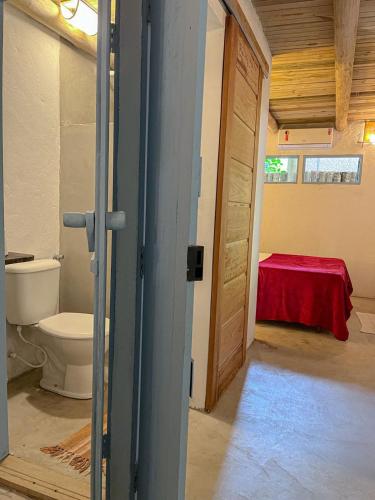 a bathroom with a toilet and a room with a table at Casinha do Rio in Caraíva