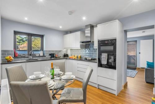 a kitchen with white cabinets and a table and chairs at Isabel's wing! A stunning 2 bedroom Property in Norwich