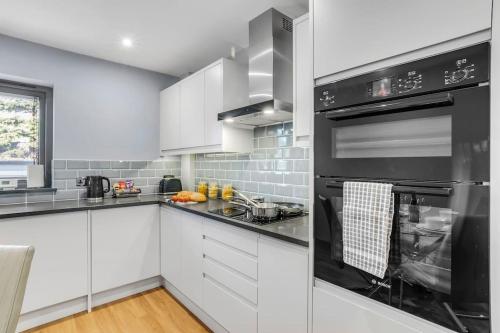 a kitchen with white cabinets and black appliances at Isabel's wing! A stunning 2 bedroom Property in Norwich