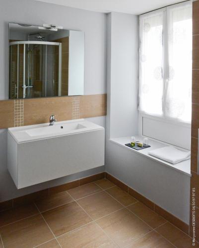 une salle de bain avec un lavabo blanc et une fenêtre dans l'établissement Logis Hôtel Restaurant de France, à Isigny-sur-Mer