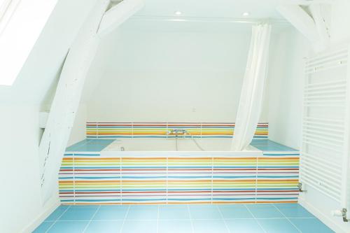 a bathroom with a tub with a colorful tile floor at Maison Bossoreil - appartement Aubance in Angers