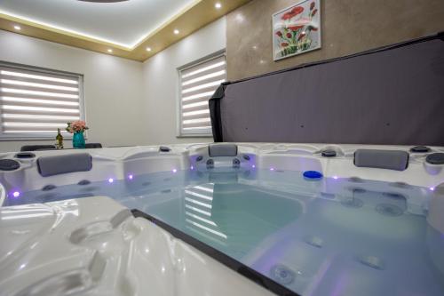 una grande vasca in una stanza con tavolo e sedie di Lux Apartment jacuzzi - Mermer Brkić 
