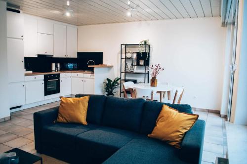 a living room with a blue couch and a kitchen at Vakantieappartement DE SPUIKOM in Ostend