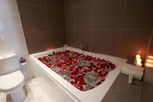uma casa de banho com uma banheira cheia de flores vermelhas em The Seven Hotel em Manama