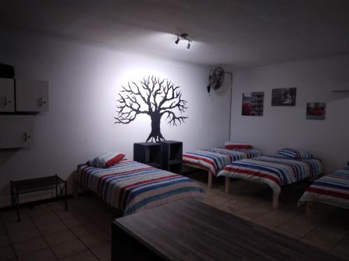 a room with three beds and a tree on the wall at FlipFlops and TreeTops in Jeffreys Bay