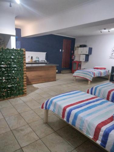 two beds sitting in a room with a kitchen at FlipFlops and TreeTops in Jeffreys Bay