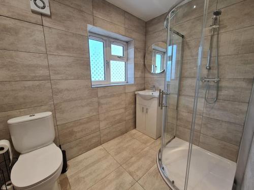 a bathroom with a shower and a toilet and a sink at Elm Park Cheerful 4-Bedroom Holiday Home in Hornchurch