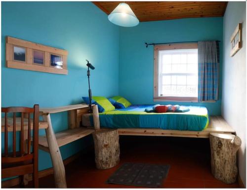 Cama en habitación con pared azul en A Barraka: your cozy house in Flores!, en Lajes das Flores