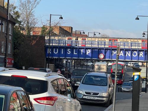 a busy city street with cars and a train under a bridge at TJ Homes - Luxury Studio Suite with Garden View - Next to tube station London in Ruislip