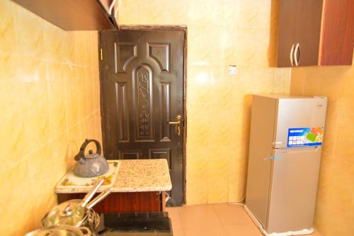 a kitchen with a black door and a refrigerator at Living Green APARTMENTS AIRPORT PICK UP in Benin City