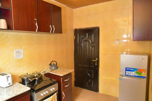 a kitchen with a black door and a refrigerator at Living Green APARTMENTS AIRPORT PICK UP in Benin City