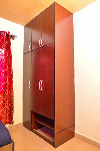 a wooden cabinet in a room with a bed at Living Green APARTMENTS AIRPORT PICK UP in Benin City