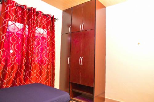 a bedroom with a red curtain and a cabinet at Living Green APARTMENTS AIRPORT PICK UP in Benin City