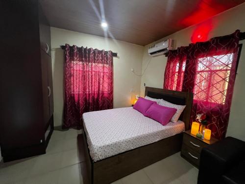 a small bedroom with a bed and red curtains at Living Green APARTMENTS AIRPORT PICK UP in Benin City