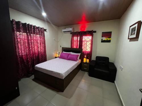 a bedroom with a bed and a chair in it at Living Green APARTMENTS AIRPORT PICK UP in Benin City