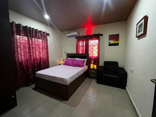 a bedroom with a bed and a chair in it at Living Green APARTMENTS AIRPORT PICK UP in Benin City