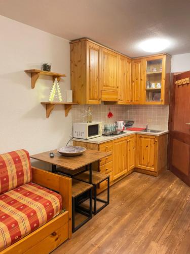 a kitchen with wooden cabinets and a table and a couch at Monolocale la terrazza sulla neve-Cervinia in Breuil-Cervinia