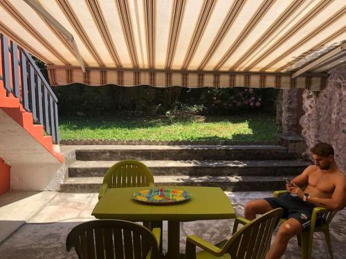 un homme assis à une table avec un téléphone portable dans l'établissement Joli appartement avec terrasse et jardin - vue sur montagne, à Bagnères-de-Bigorre