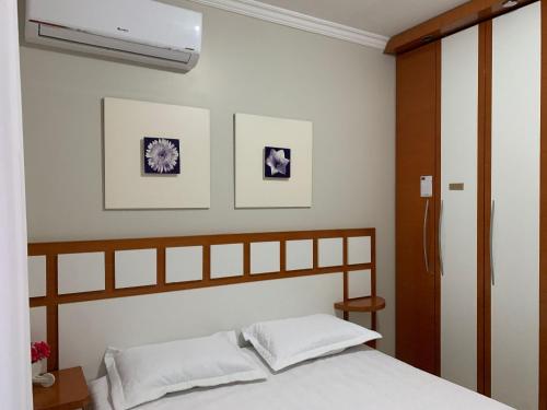 1 dormitorio con 1 cama con sábanas blancas y ventilador en Residencial Atenas I, en Bombinhas