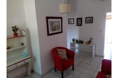 sala de estar con silla roja y mesa en Depto. próximo al Centro y Rio San Antonio en Villa Carlos Paz